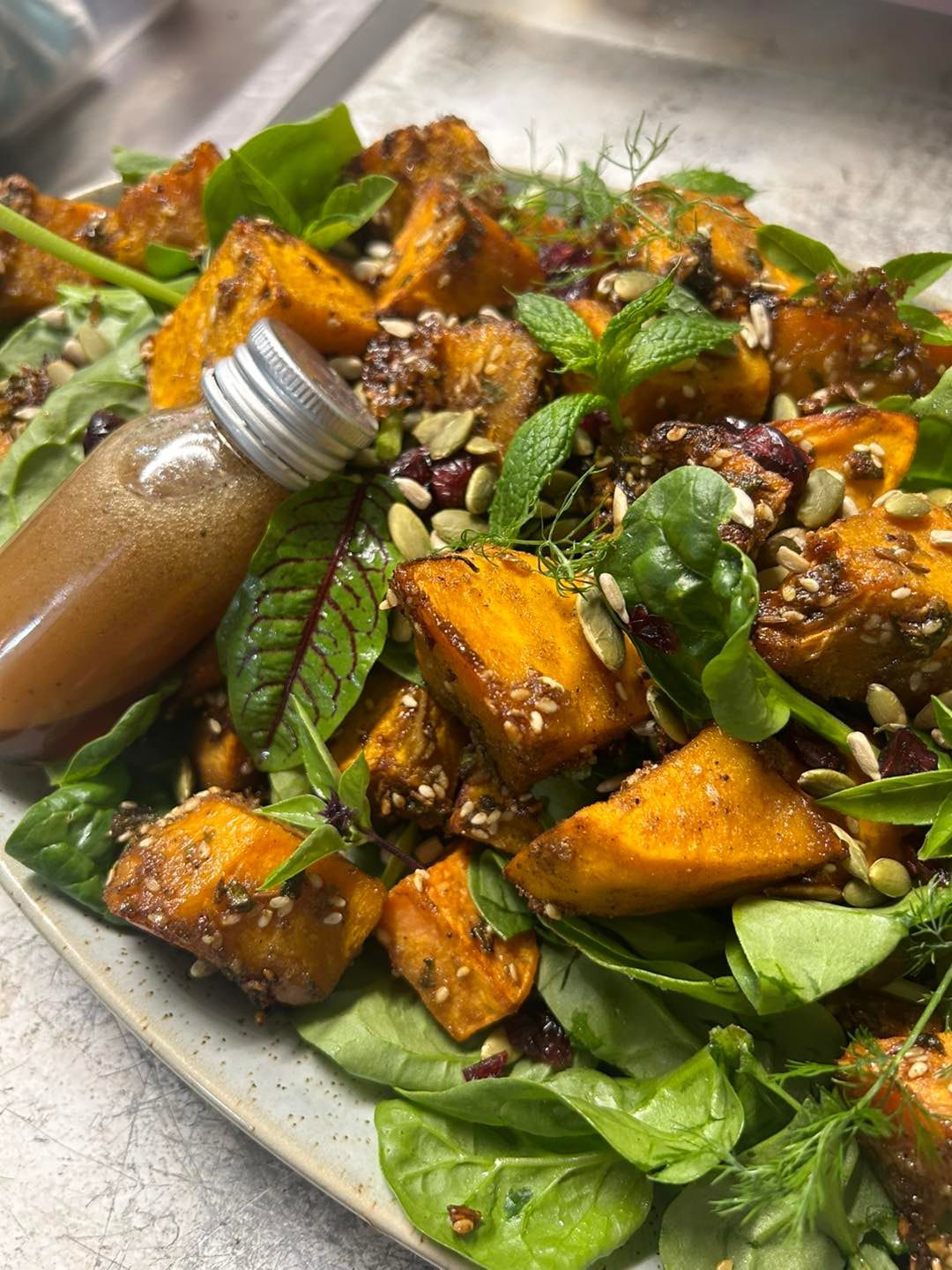 A sweet potato salad with a small bottle of dressing placed on the salad  — Amanda Douglass Catering Service in Corlette, NSW