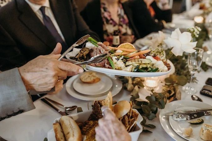 A lady is holding a plate with tongs while dishing up from a table of catering - Amanda Douglass Catering Service in Corlette, NSW