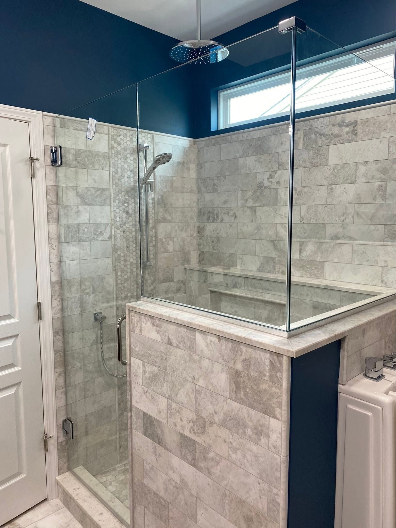 Modern tiled bathroom with glass-enclosed shower and blue walls.