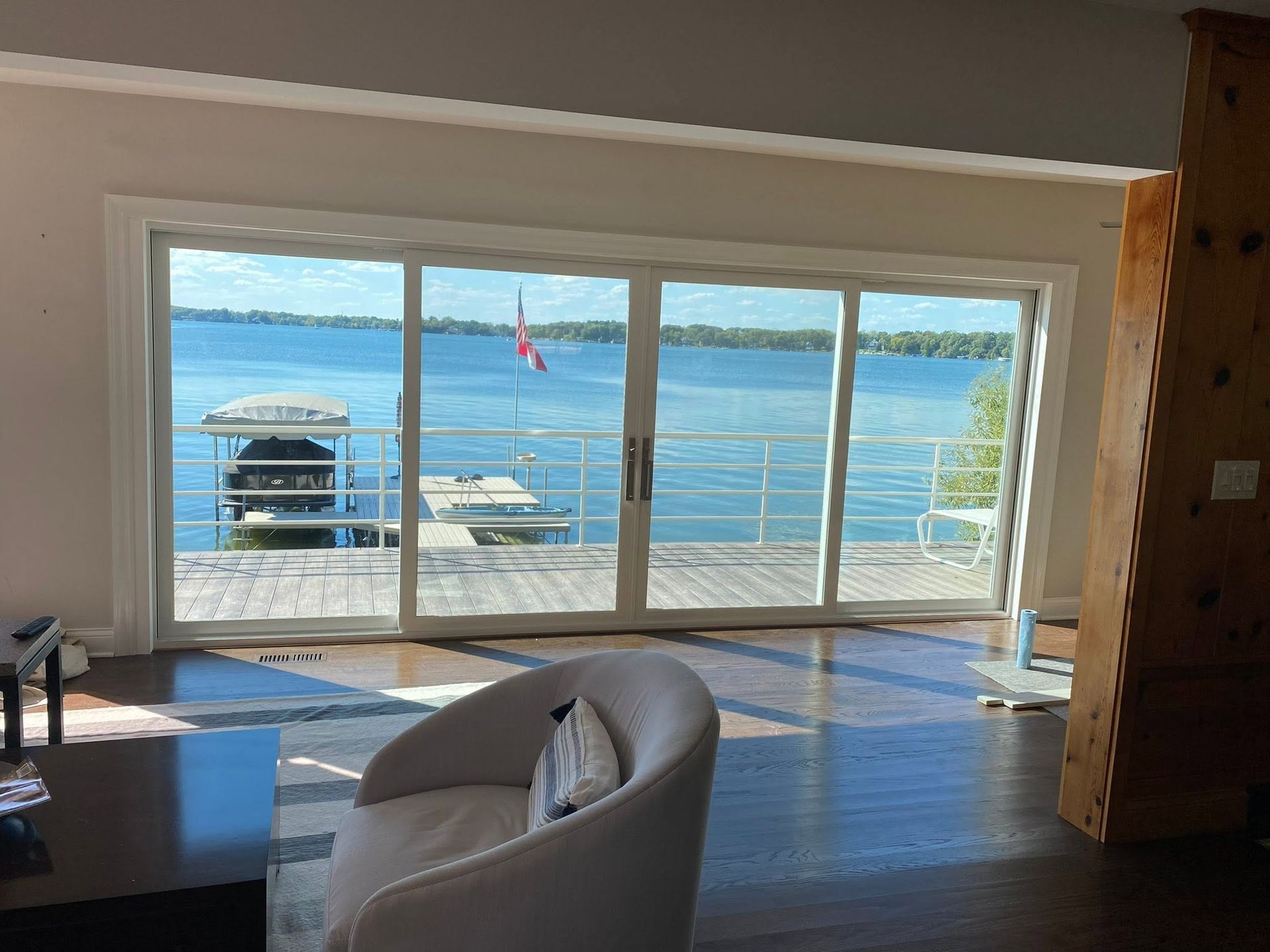 Living room with large windows overlooking a blue lake and dock at sunset