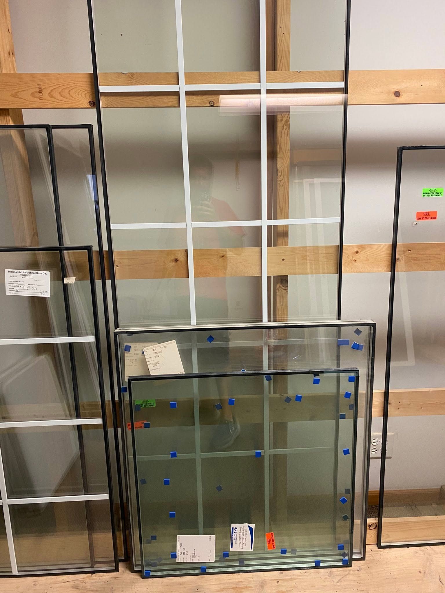 Glass window panel leaning against wall among stacked construction materials indoors