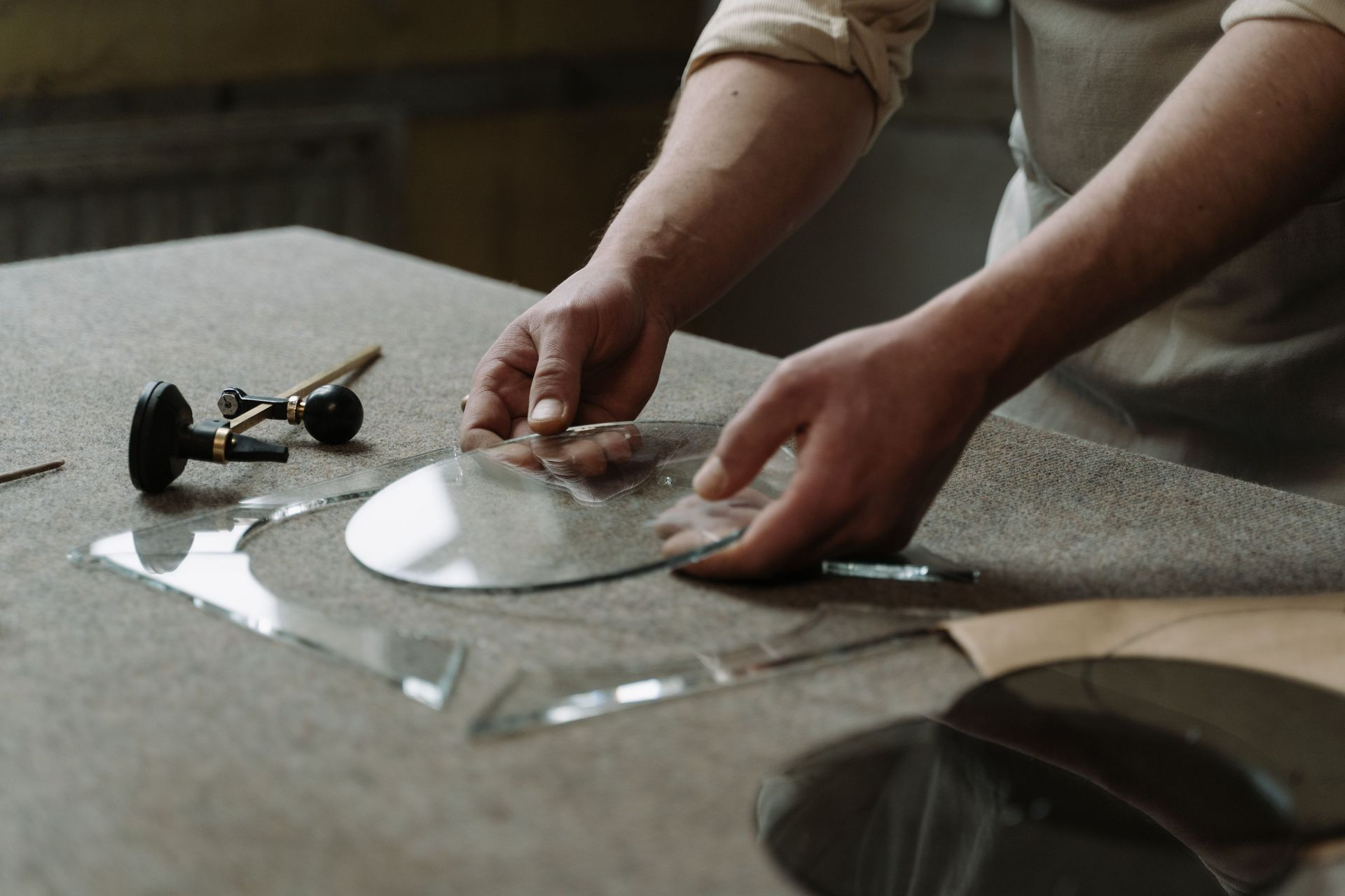 Hands cutting a clear sheet on a table beside a metal dome and tools