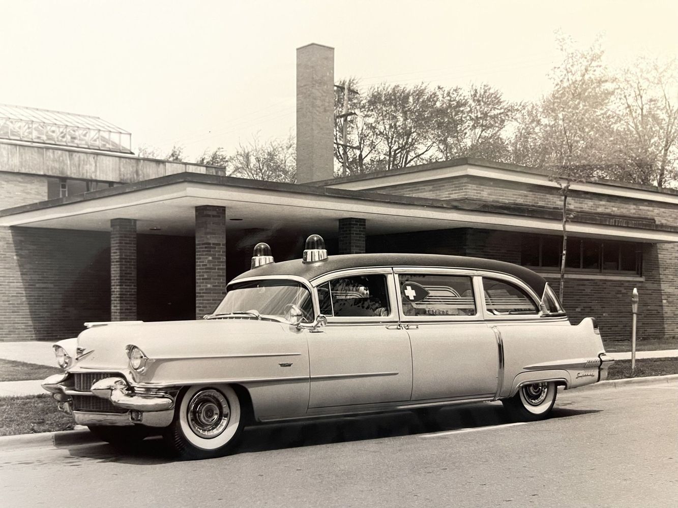 Vintage station wagon parked in front of a house, with two people visible through the windows.