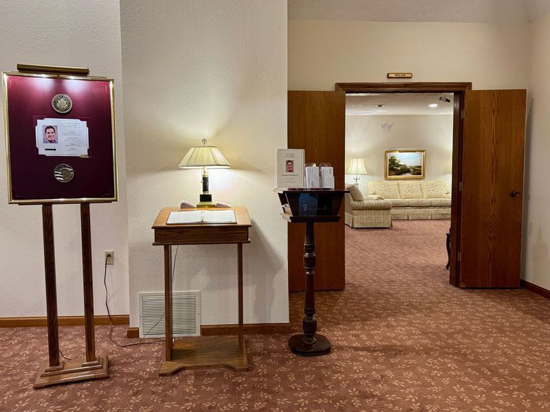 Hotel lobby with check-in desk, lamp, signboard, and open doorway to a seating area.