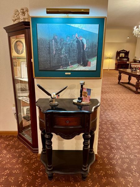 Hallway with a framed underwater artwork above a small wooden table holding a model airplane and books