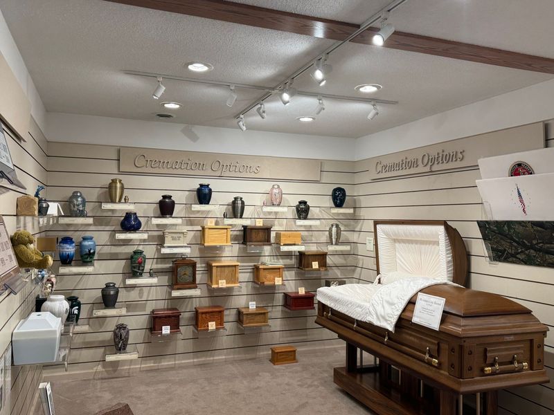 Casket showroom with display shelves and a white-lined coffin on a wooden stand