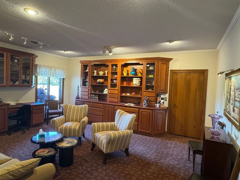 Cozy living room with striped armchairs, wooden cabinets, coffee table, and patterned carpet
