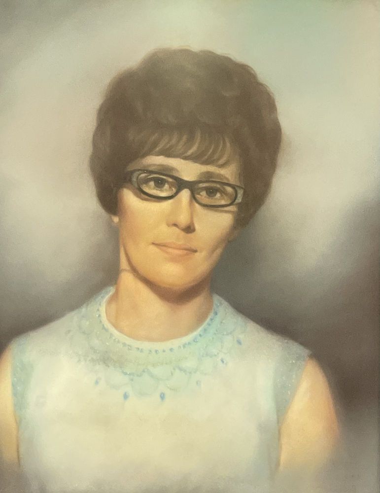 Portrait of a person with dark hair, glasses, and a light blue top against a soft gray background