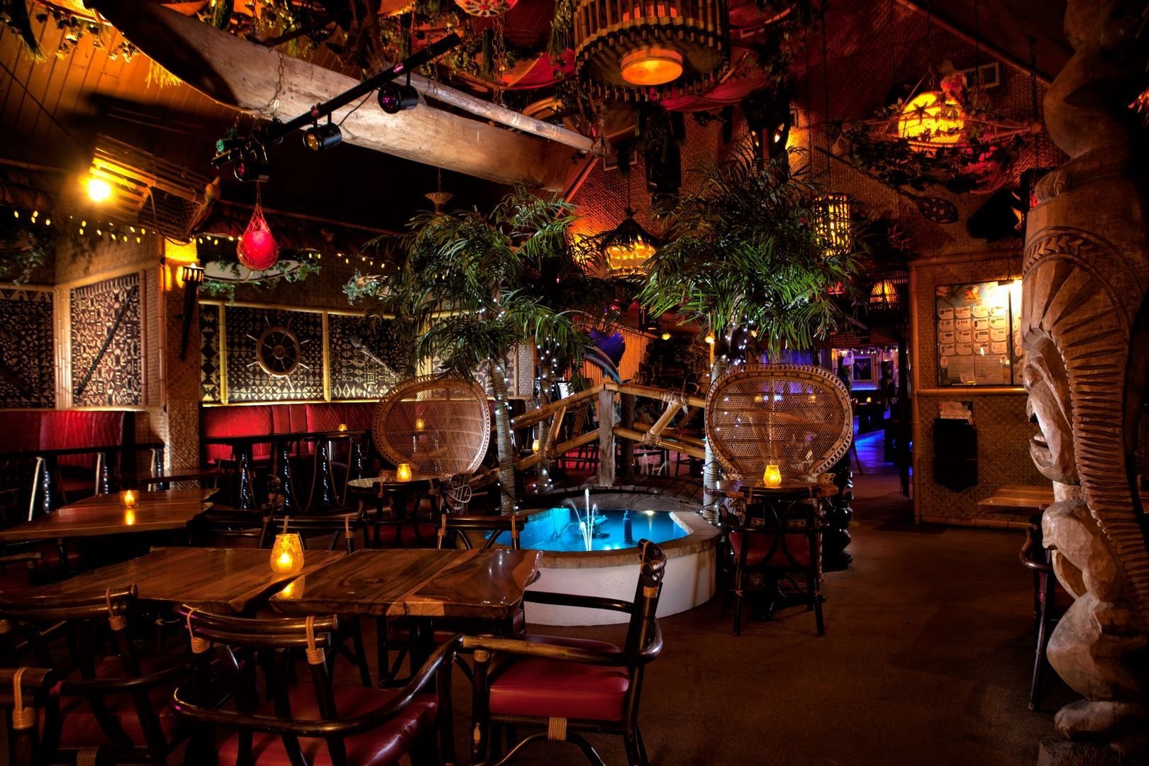 Un restaurant avec tables et chaises et un bassin au milieu de la pièce.