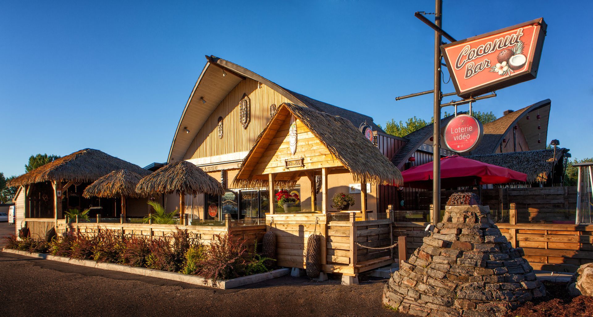 Un restaurant avec un toit de chaume et une pancarte indiquant « hawaïen » dessus