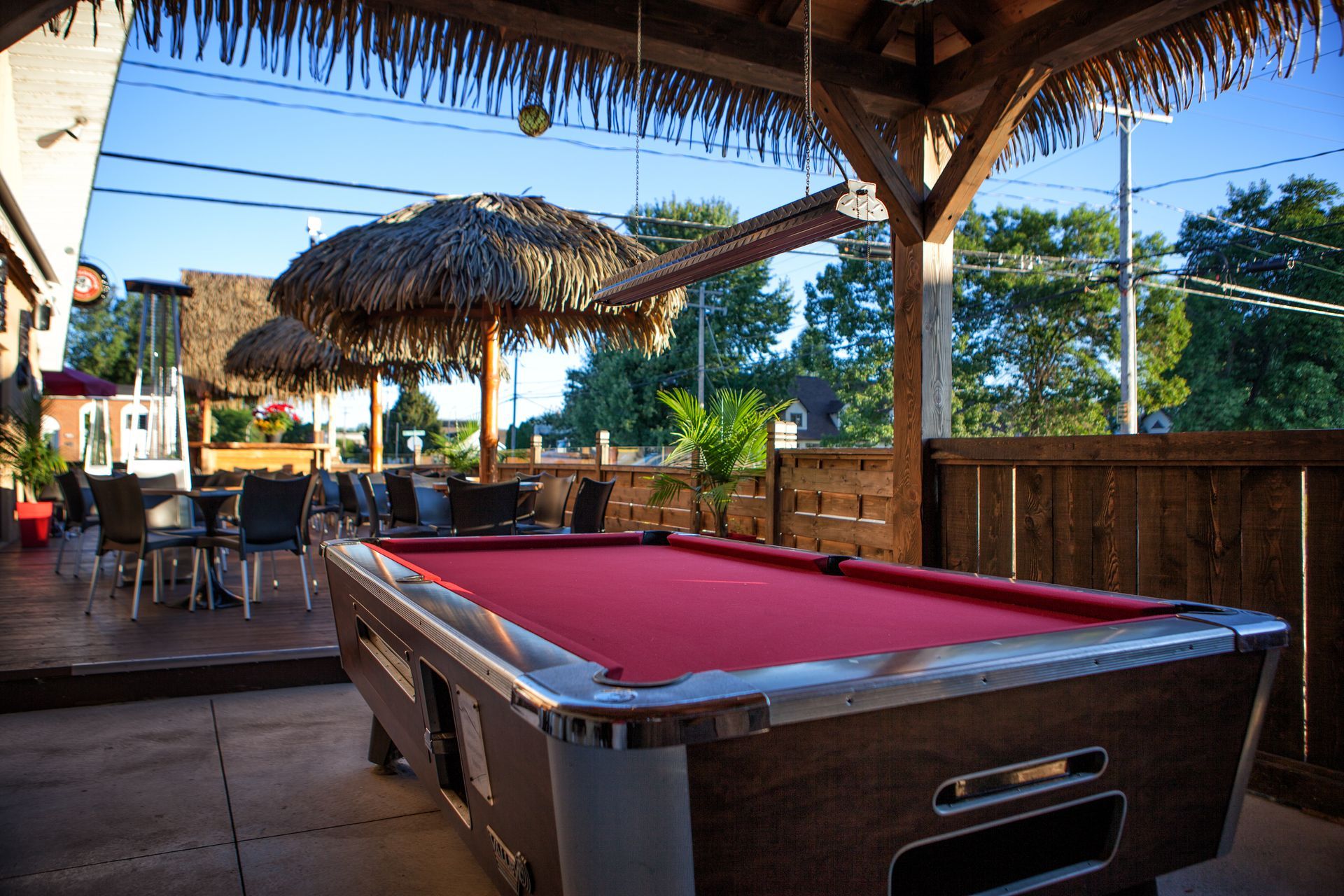 Une table de billard est posée sur une terrasse sous des parasols.