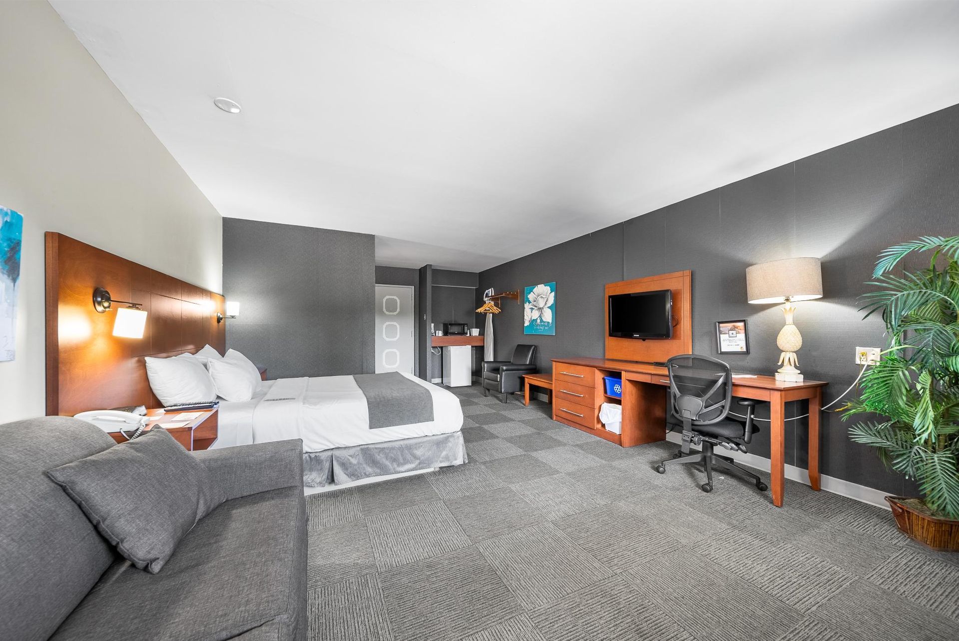 Une chambre d'hôtel avec un lit king size, un canapé, un bureau et une télévision.