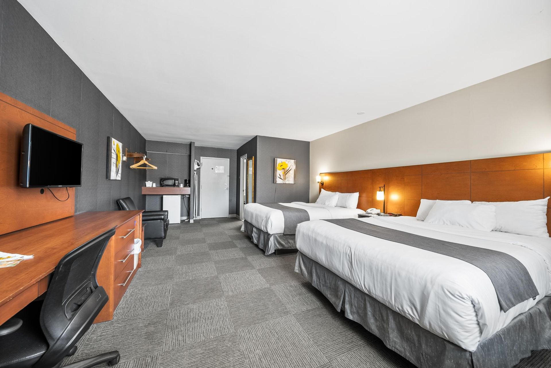 Une chambre d'hôtel avec deux lits, un bureau et une télévision à écran plat.