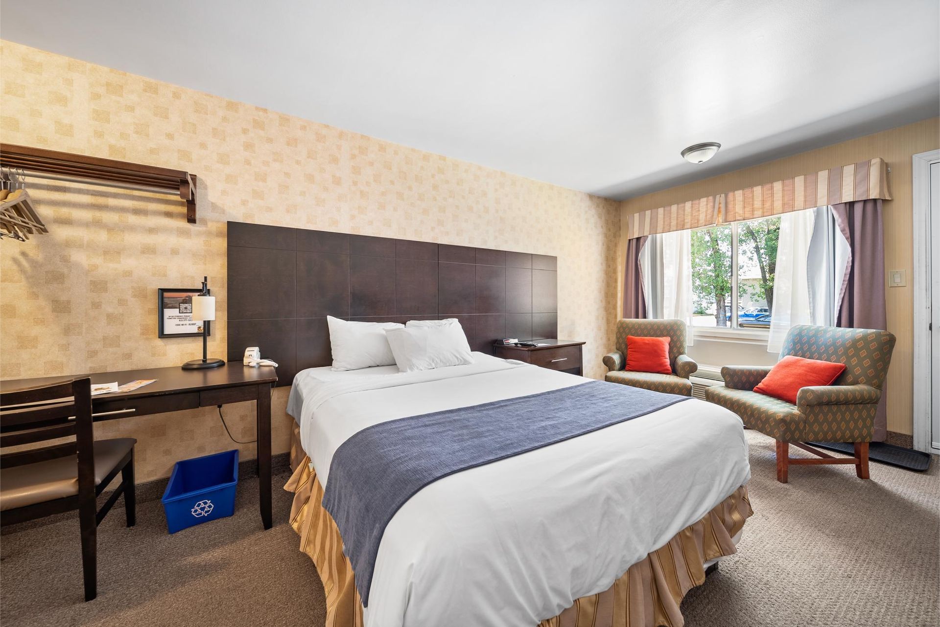 Une chambre d'hôtel avec un lit king size, un bureau, une chaise et une fenêtre.