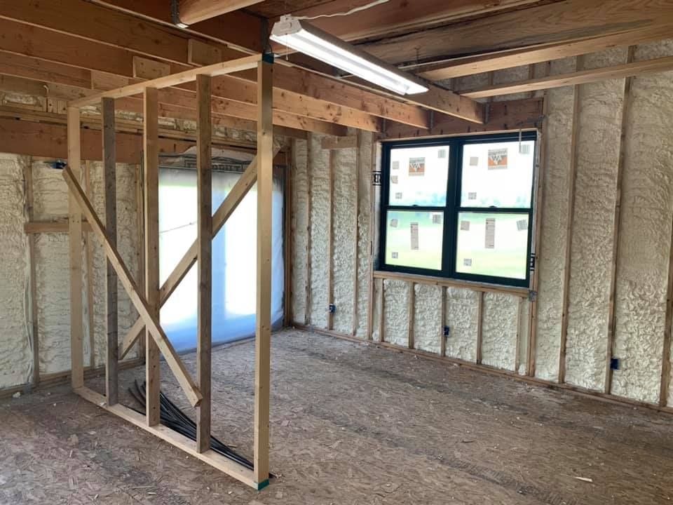 Unfinished room with exposed wood framing, insulated walls, and a window letting in daylight.