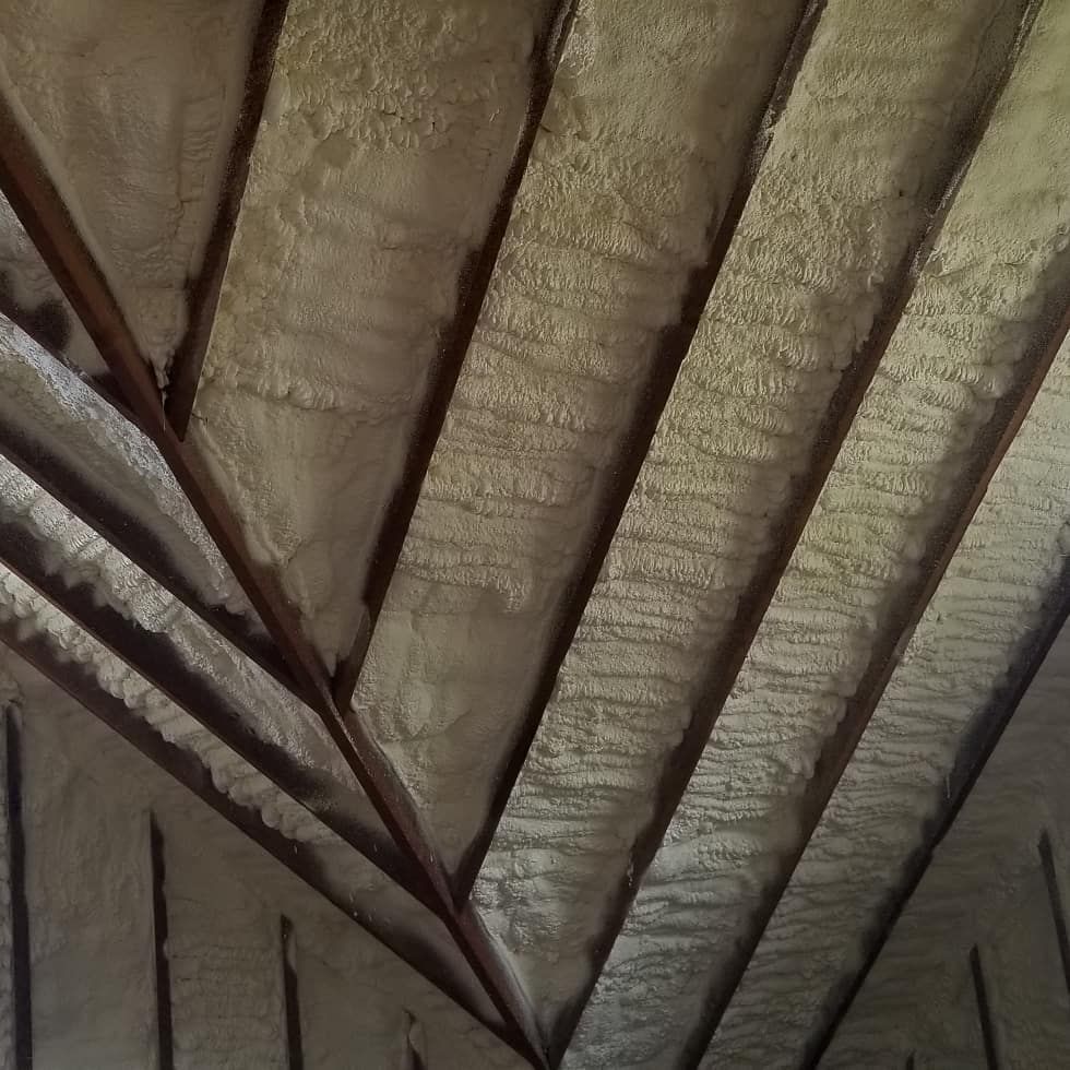 Underside of a roof with exposed wooden beams and rough insulation panels.