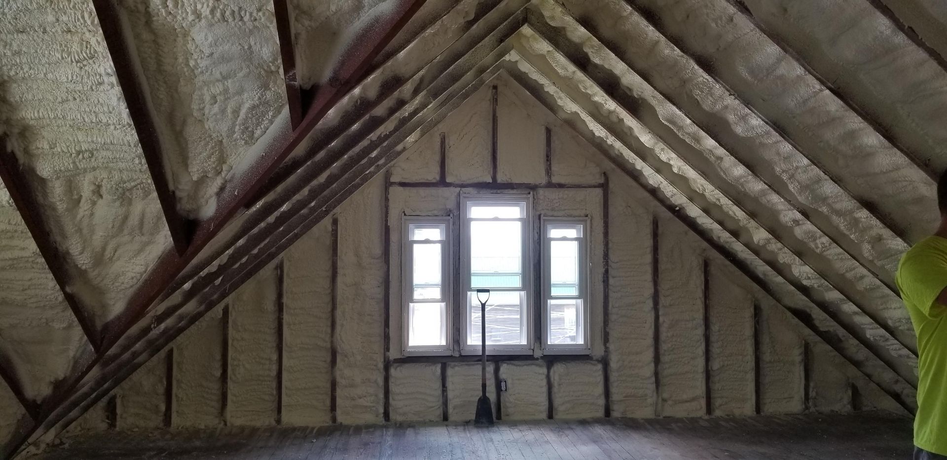 Attic interior with exposed beams and a small window centered on the far wall