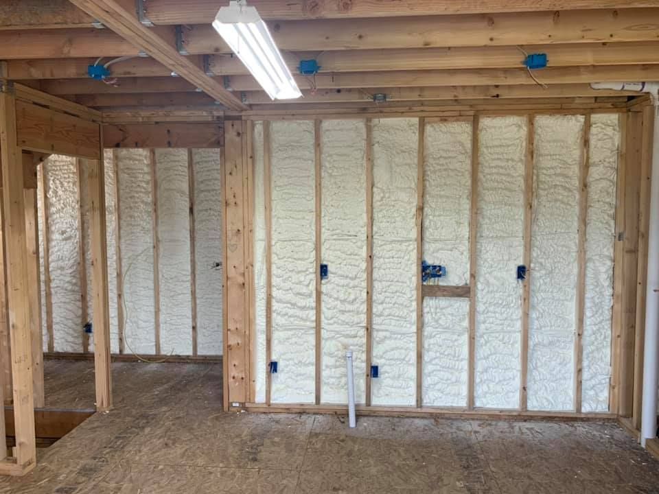 Unfinished room with exposed wooden framing and spray foam insulation on the walls and ceiling.