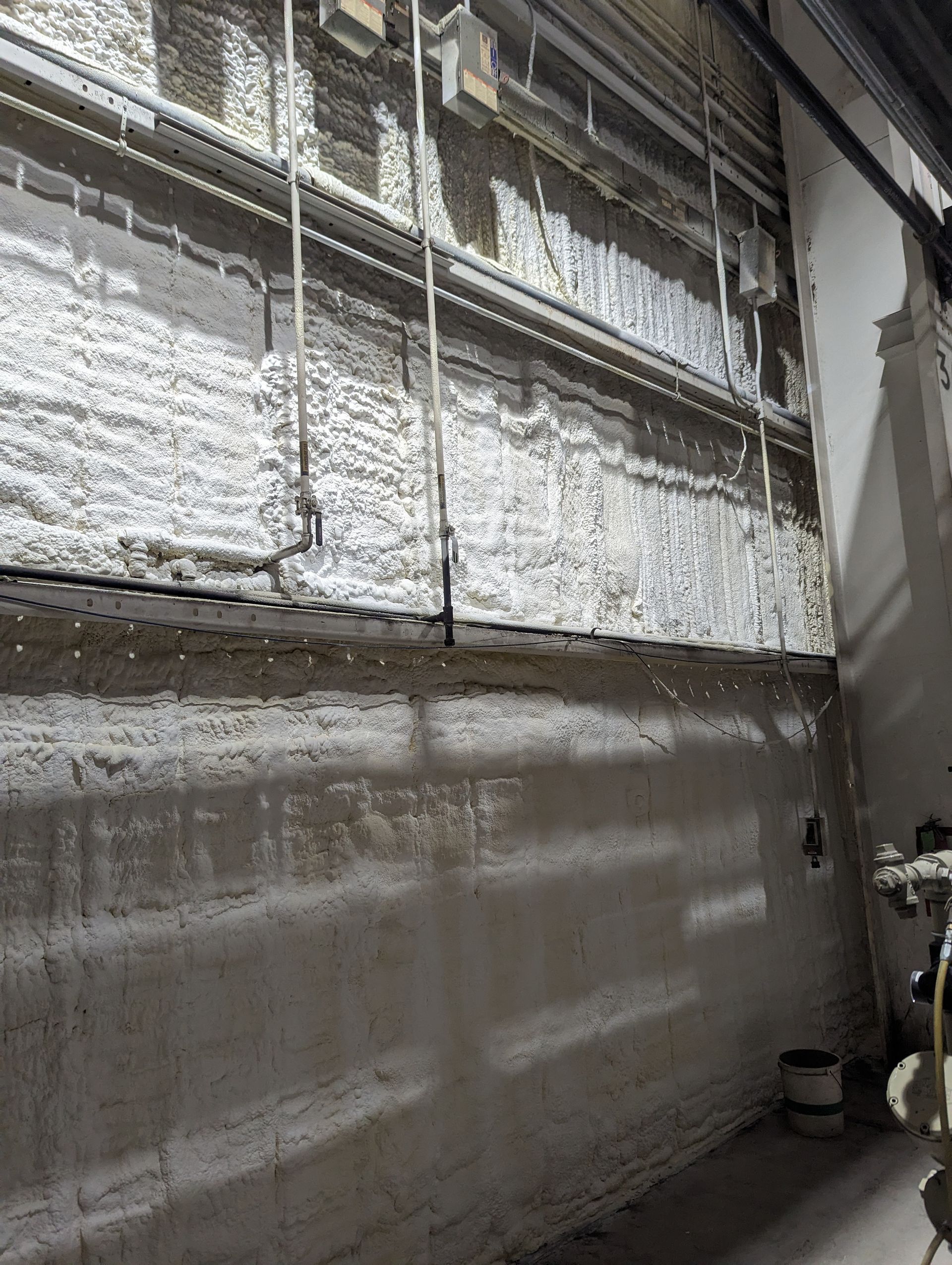 Industrial wall covered with reflective insulation and pipes in a utility room