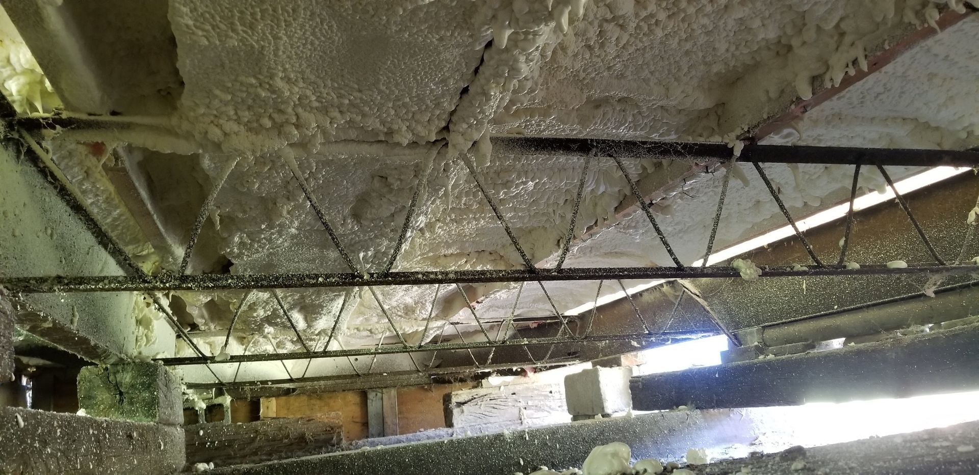 Damaged ceiling with exposed beams and hanging debris in an abandoned interior room.