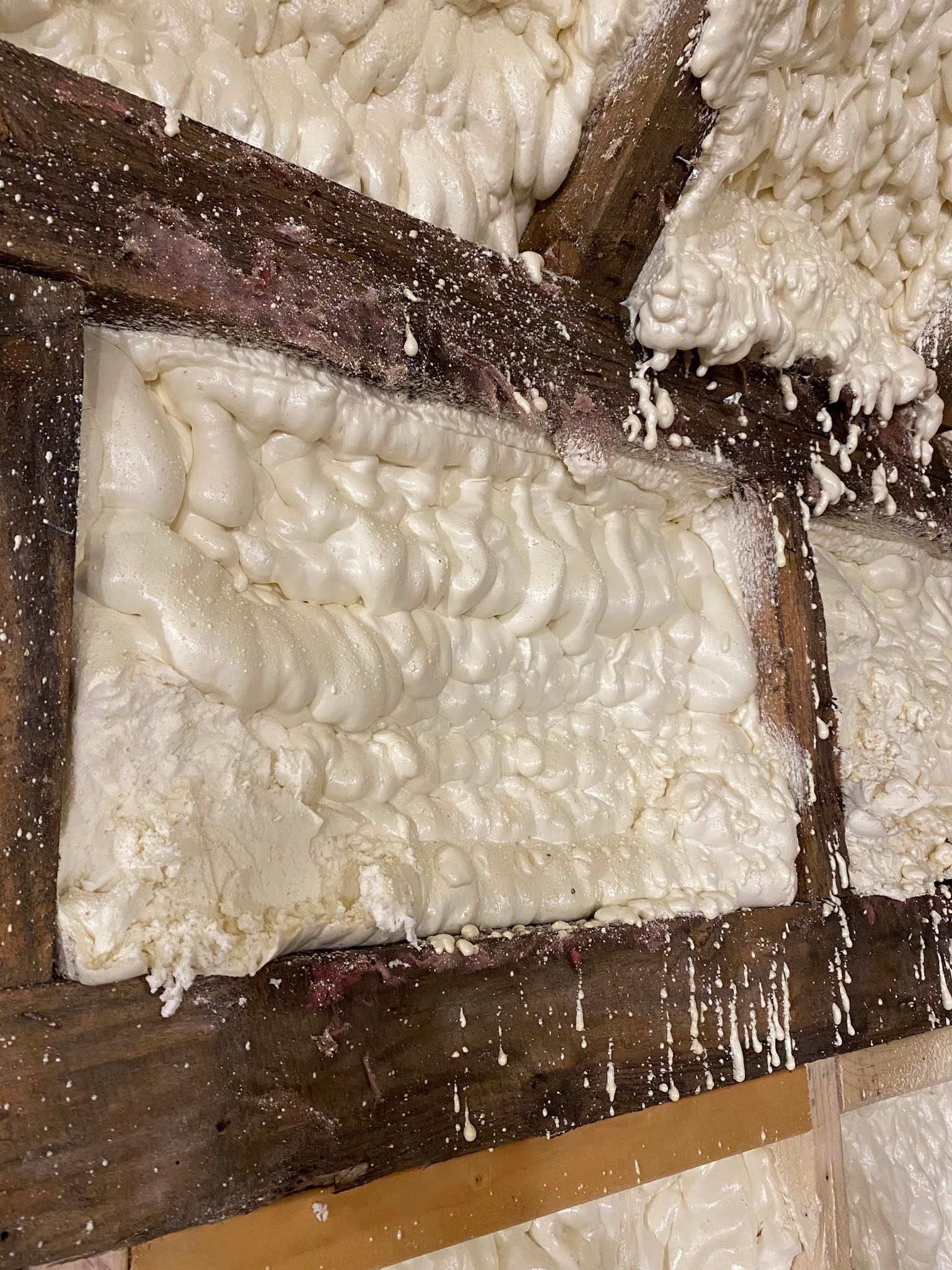 White foam insulation panels mounted on a wooden frame inside a wall cavity