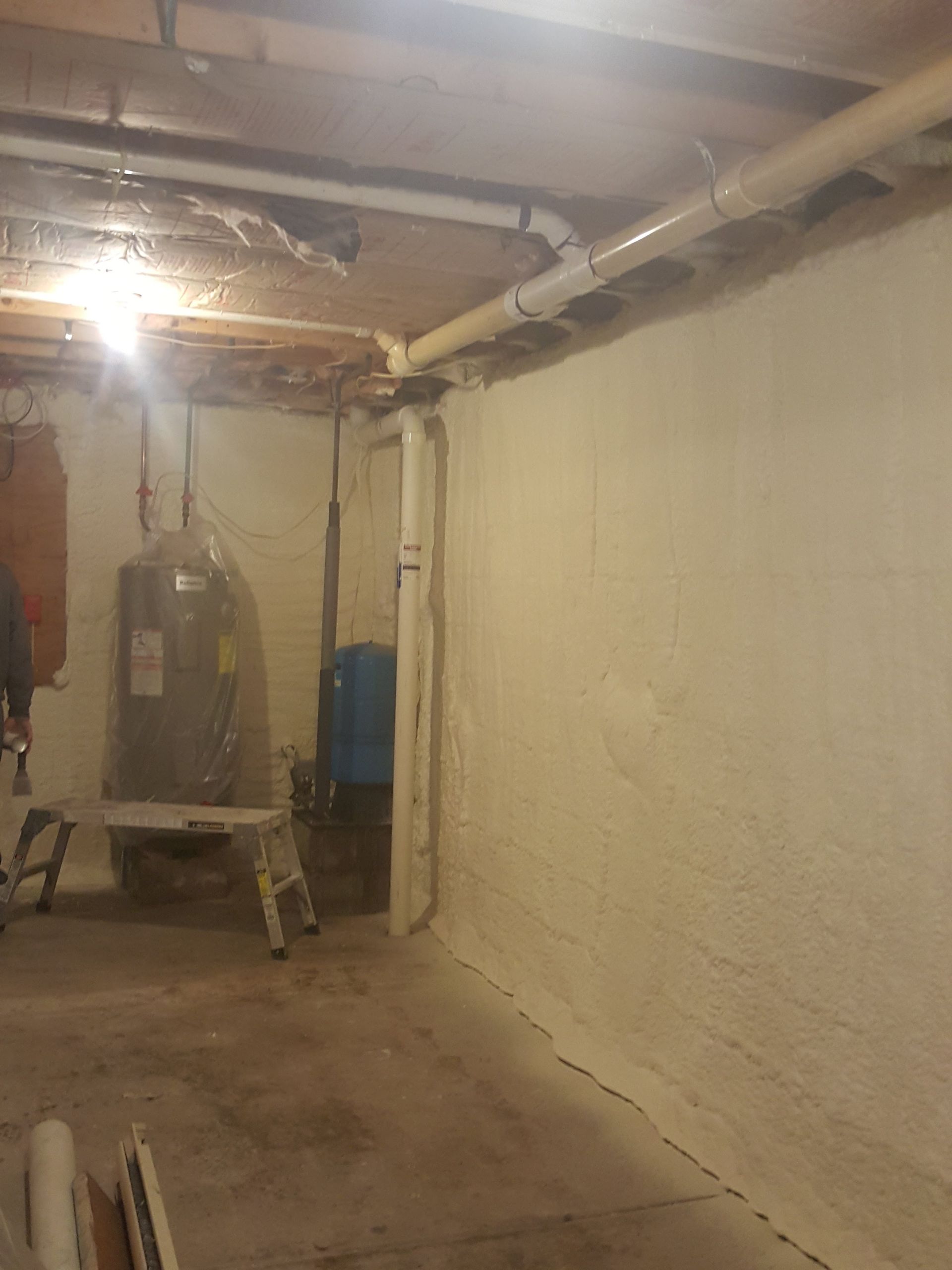 Basement with a boiler, exposed pipes, and a rough concrete floor under a low ceiling.