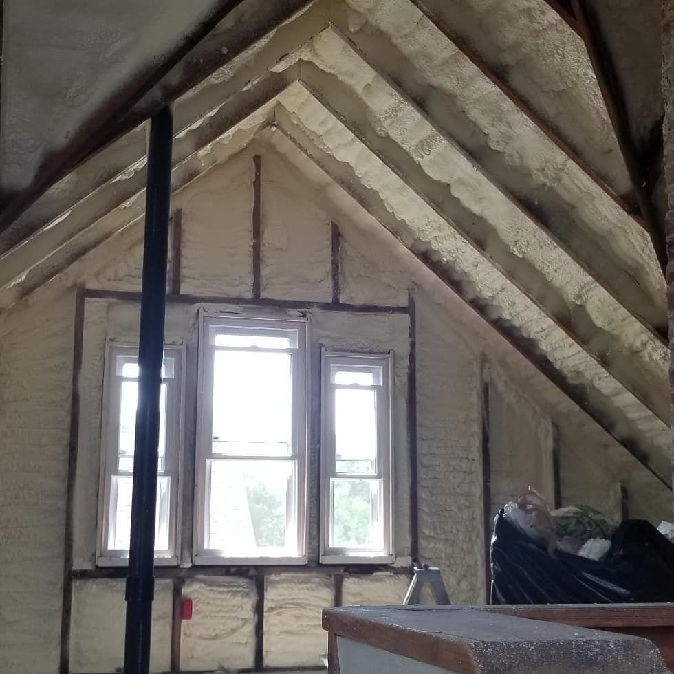 Unfinished attic with exposed rafters and a small window letting in daylight.