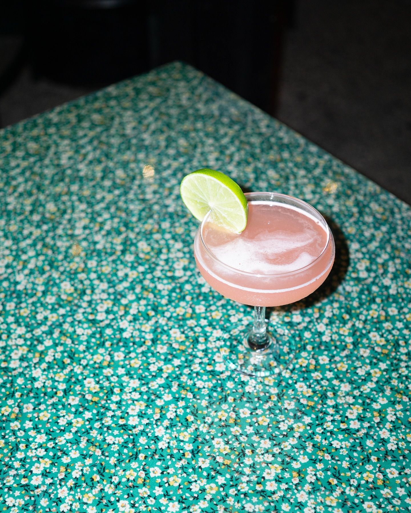 Pink Cocktail With Lime Garnish on a Patterned Green Table — Village Bicycle Noosa in Noosa Heads, QLD