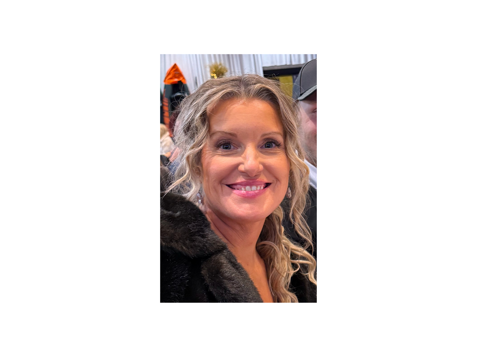 A woman in a black hoodie is holding a tablet and smiling