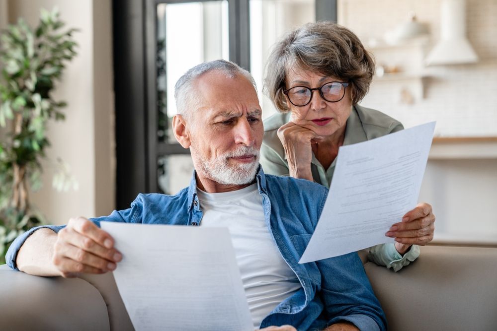 Two people on a couch reviewing documents in a bright living room