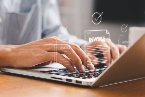 Hands typing on a laptop with invoice icons overlaid on the screen