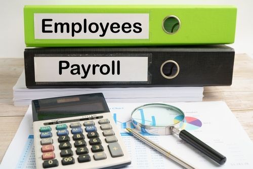 Employees and Payroll folders with calculator, magnifying glass, and pen on desk