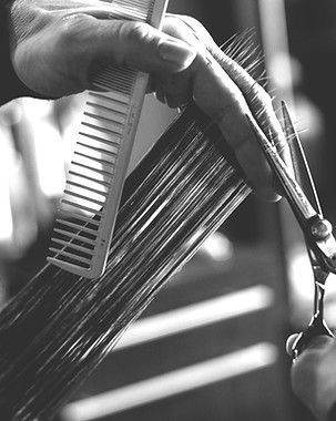 Close-up of a hairstylist combing wet hair with scissors nearby.
