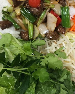 Rice noodles topped with beef, green onions, bean sprouts, herbs, and a red chili pepper