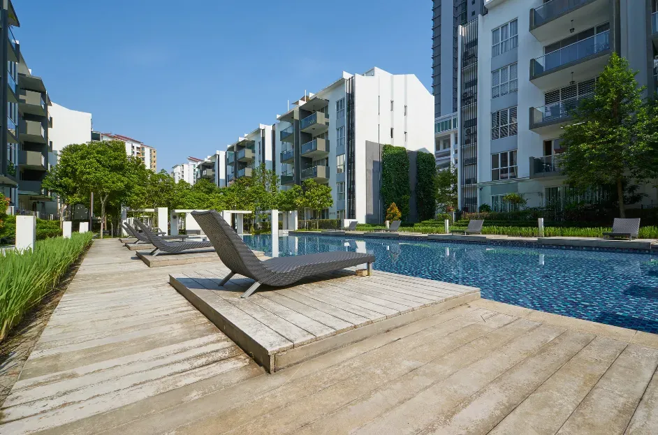Modern apartment pool deck with lounge chairs and blue water under a sunny sky