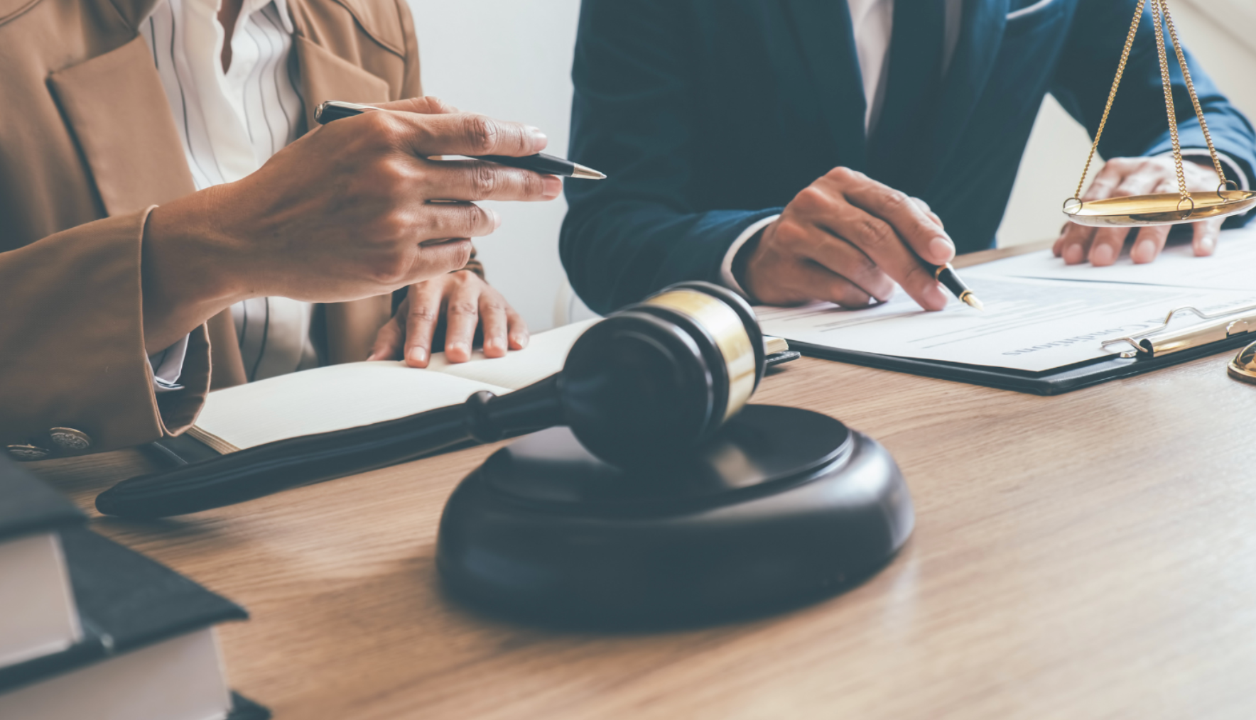 A gavel on a desk during a meeting with two people reviewing documents and taking notes.
