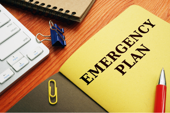 Emergency plan folder on desk with keyboard, notebook, and pen clips.