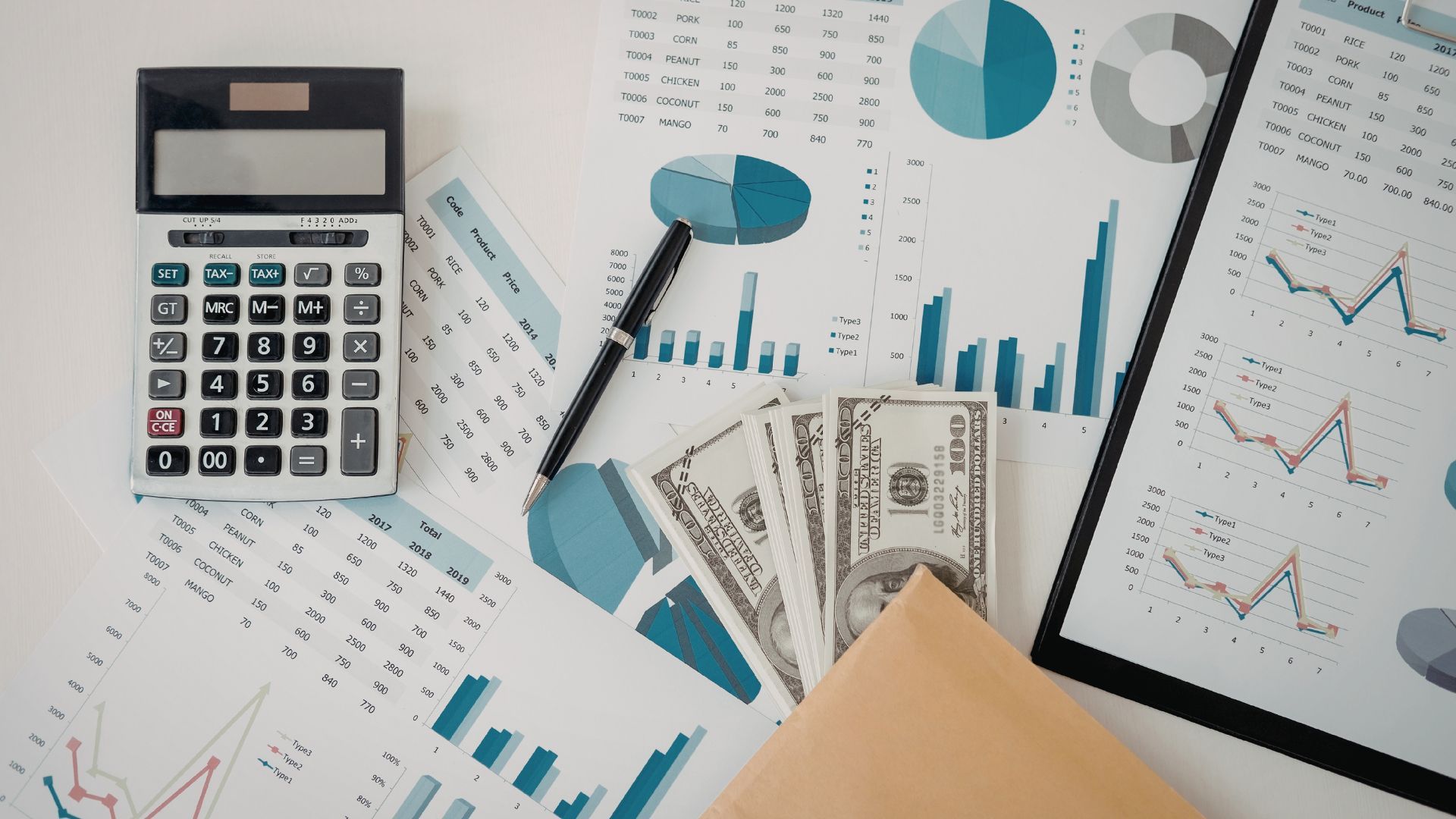 Calculator, charts, and cash on a desk, showing financial data and analysis.