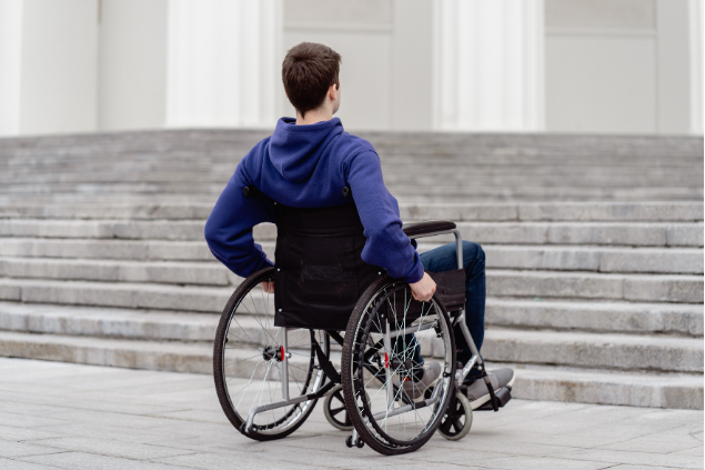 Person in a wheelchair facing a wide stone staircase outdoors