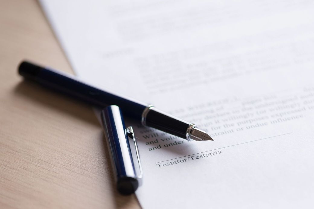 Una penna nera appoggiata su un foglio di carta stampata su una scrivania, con una seconda penna nelle vicinanze.