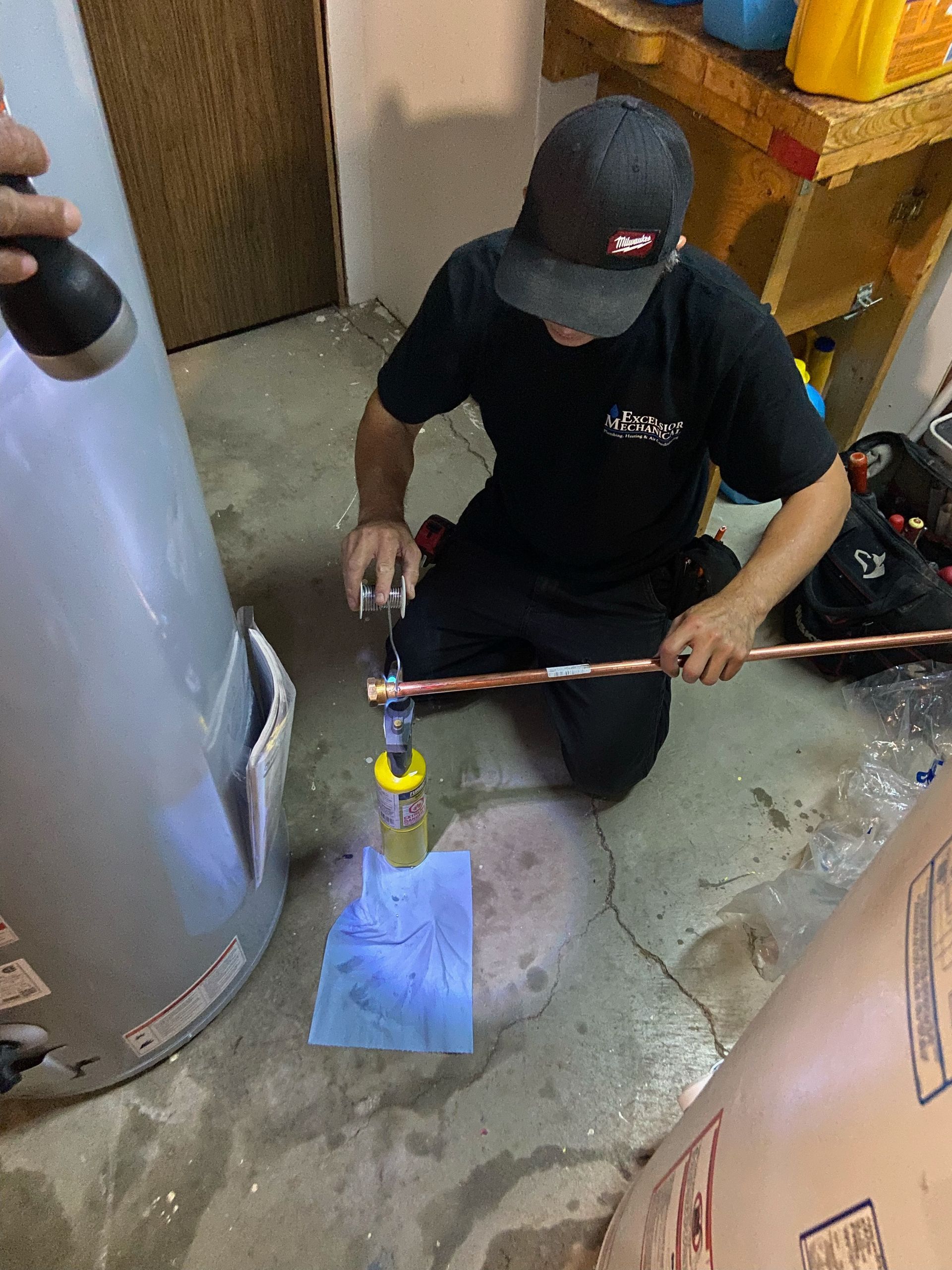 a man is kneeling down in front of a water heater .