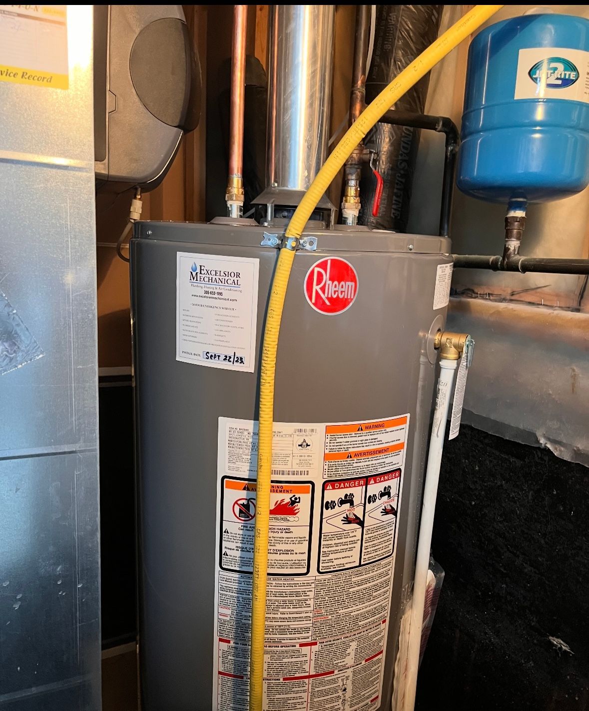 A gray water heater with a yellow hose attached to it.