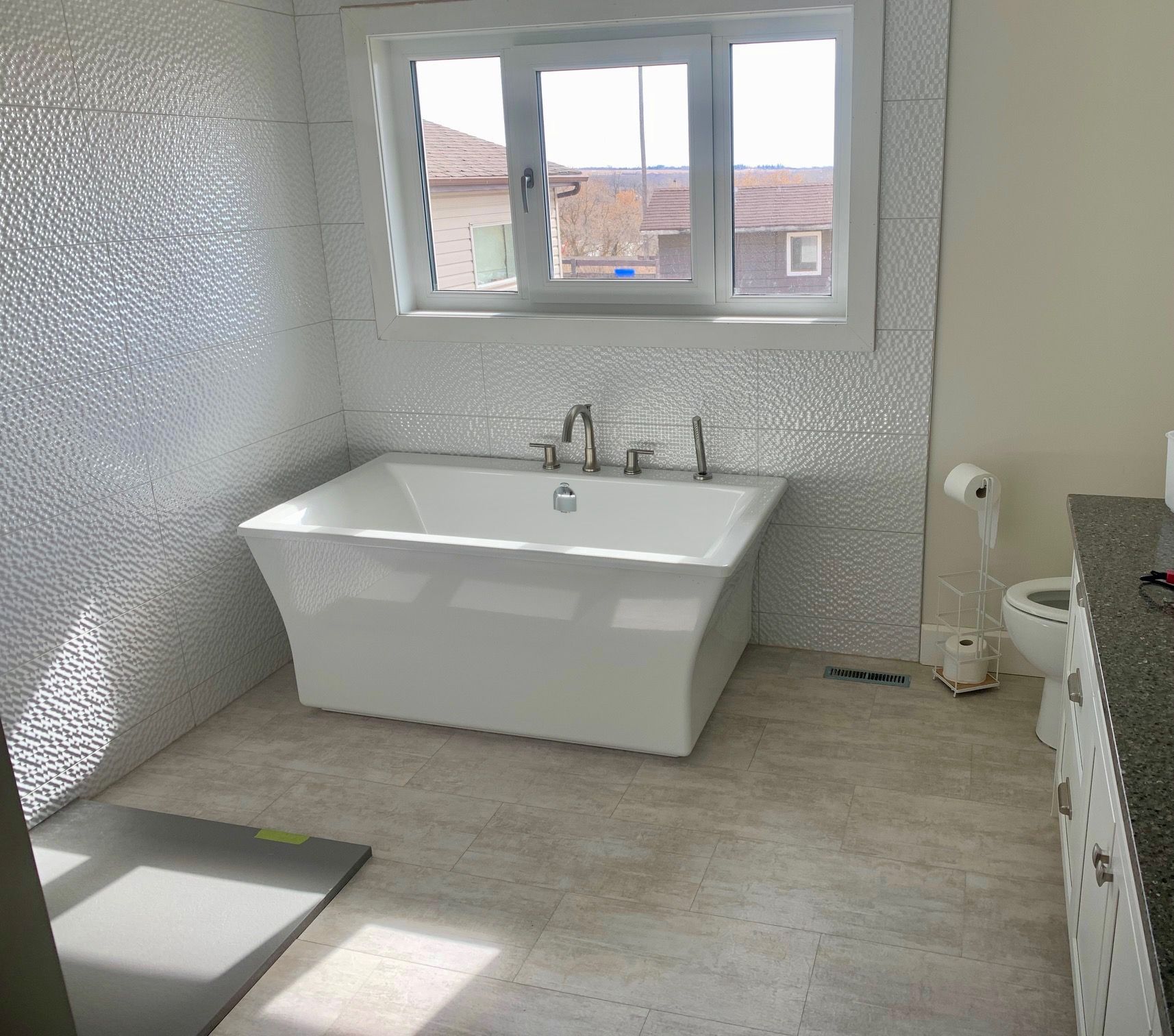A bathroom with a tub a toilet and a window