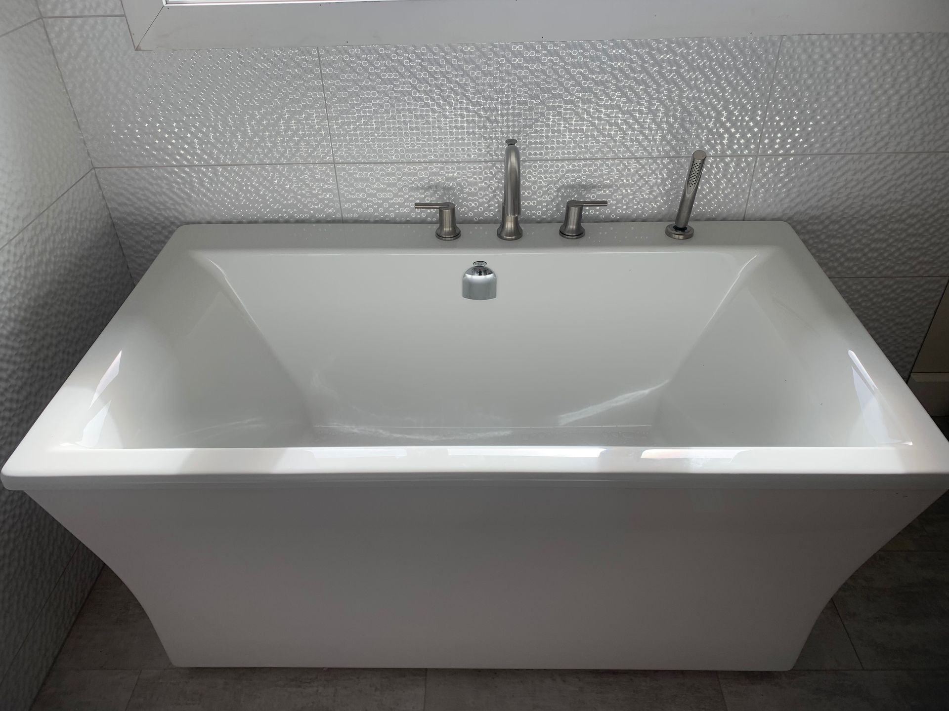 a white bathtub is sitting in a bathroom next to a window .