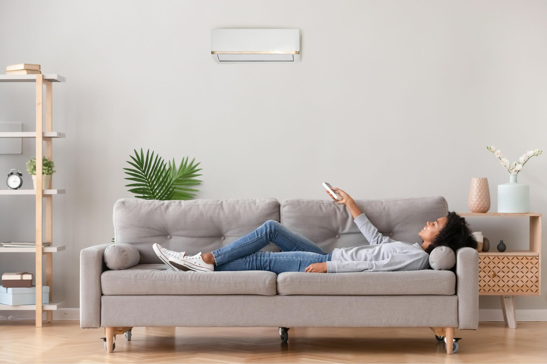 a woman is laying on a couch in a living room holding a remote control .