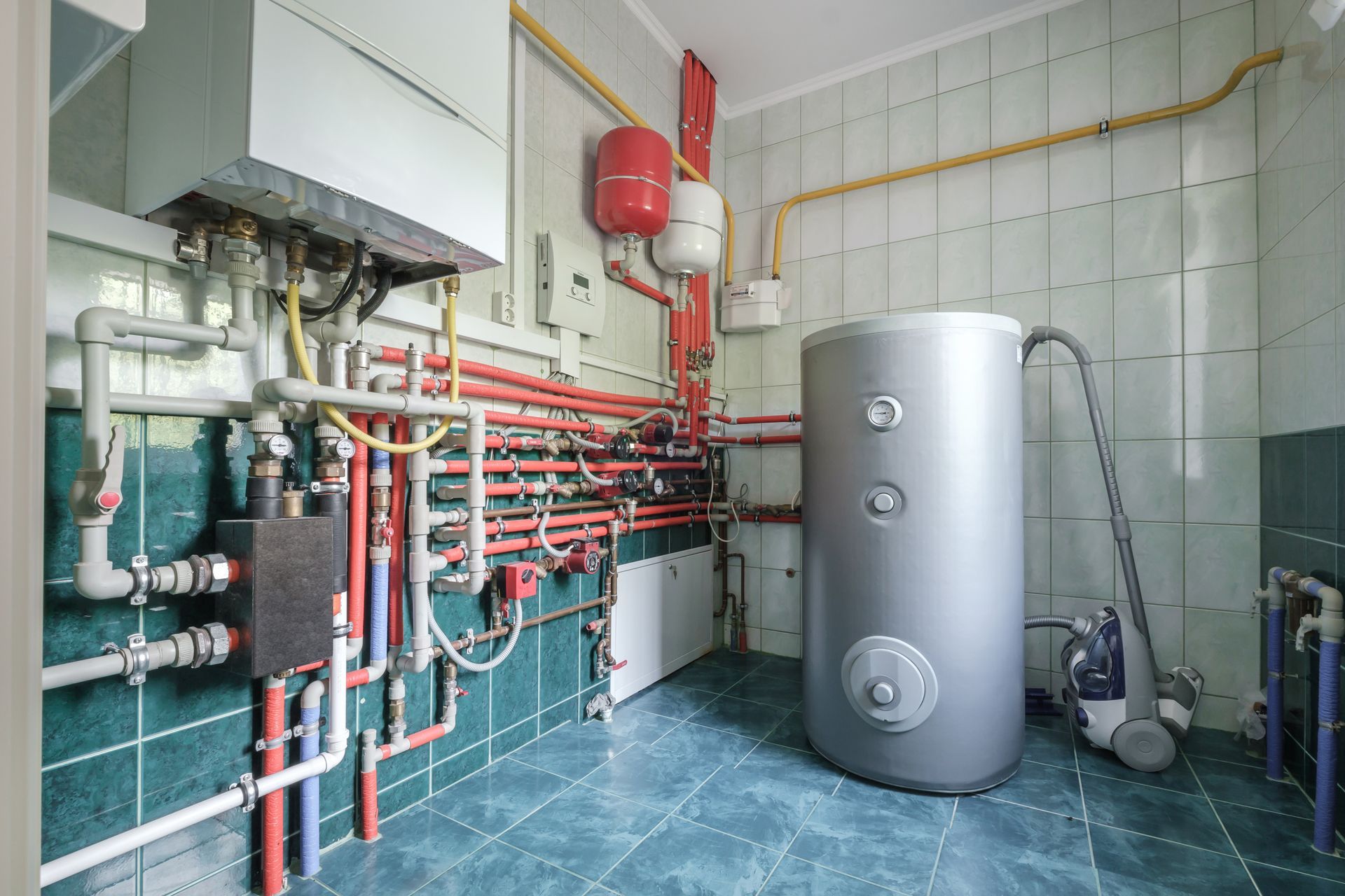 a room filled with lots of pipes and a water heater .