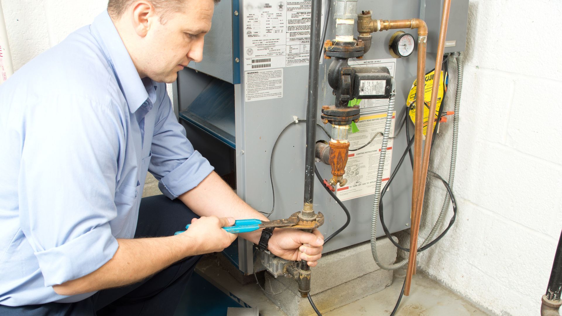 a man is working on a heating system in a basement .