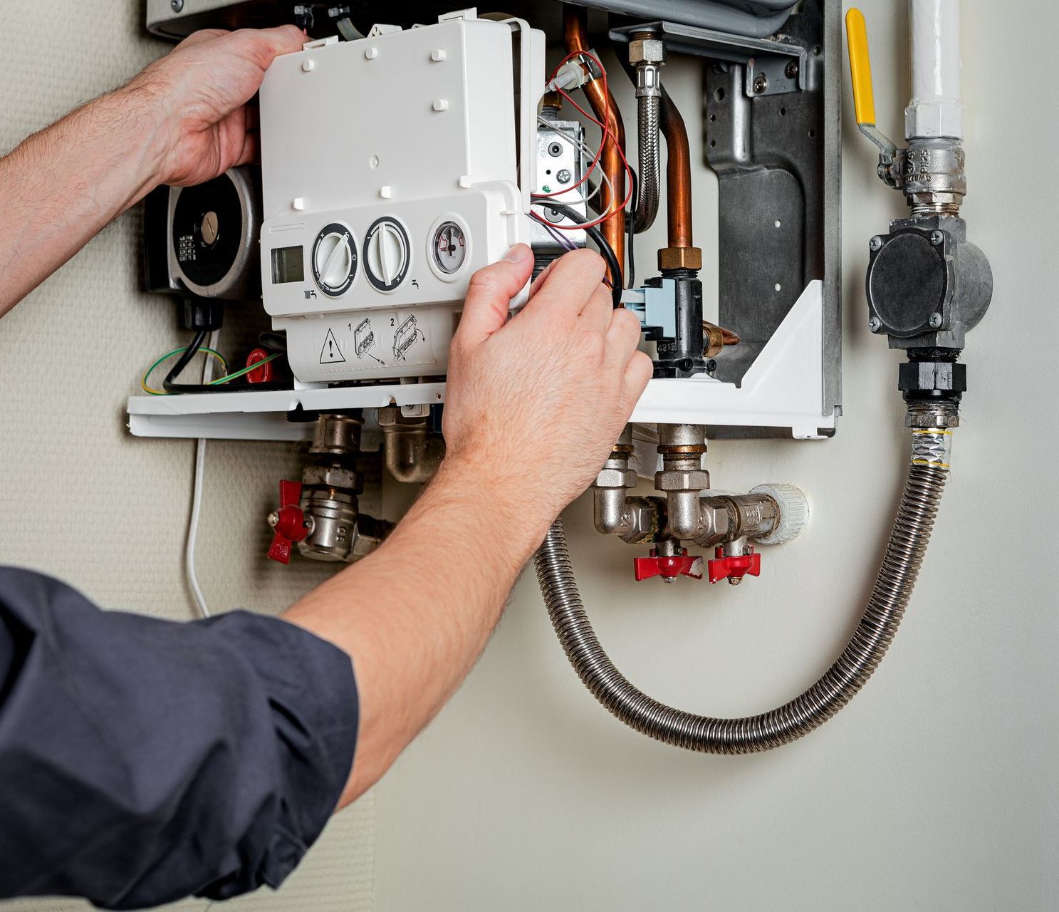 a man is fixing a water heater with a hose attached to it