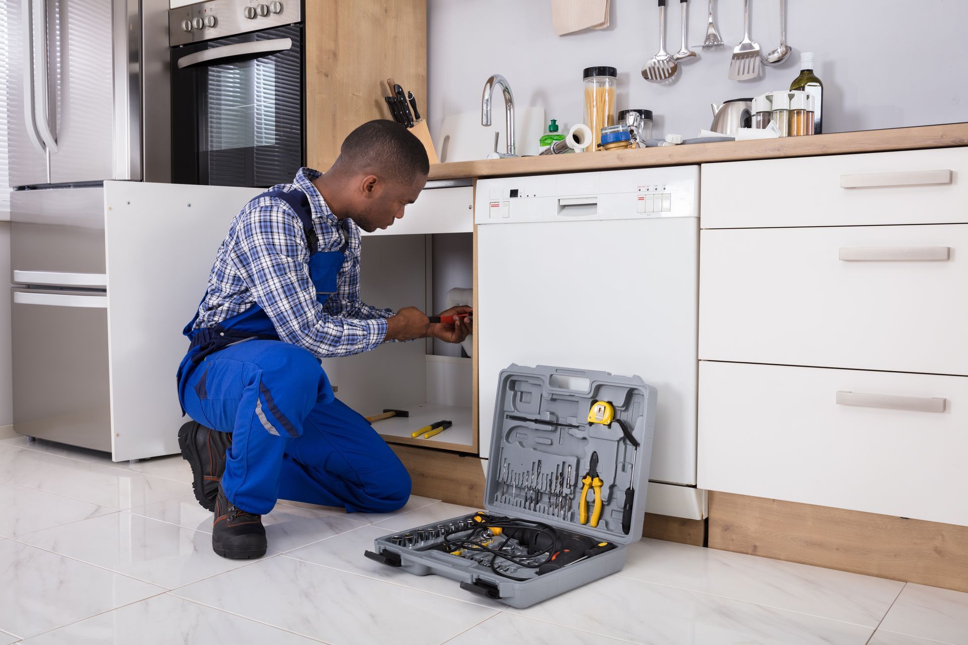 a plumber is fixing a sink in a kitchen .