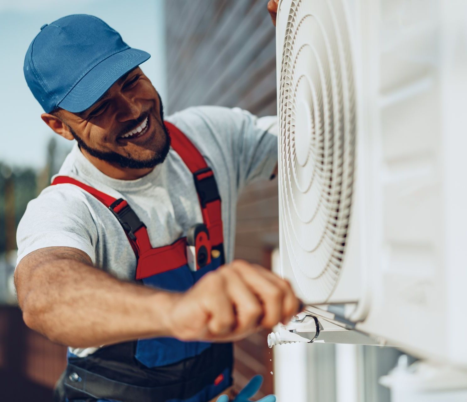 a man wearing a blue hat is working on a fan